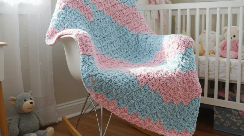 Soft pastel-colored crochet baby blanket made with shell stitch, folded neatly on a white nursery chair.
