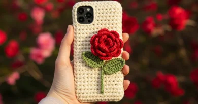 Beige crochet phone case with a red 3D rose and green leaves, handmade with worsted cotton yarn.