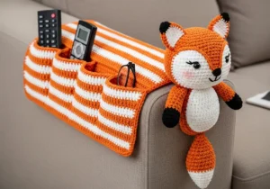 Crochet Sofa Arm Organizer Pattern with orange and white stripes and a fox amigurumi decoration