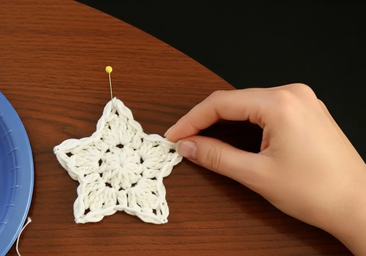 Small five-point crochet star ornament in cream bulky yarn hanging from jute on a decorated Christmas tree